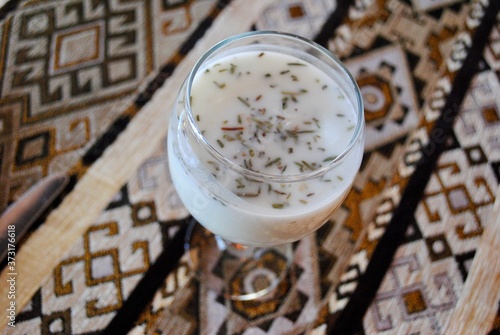 Ayran with fresh herbs in glasses. Traditional Turkic yogurt drink on table cloth.