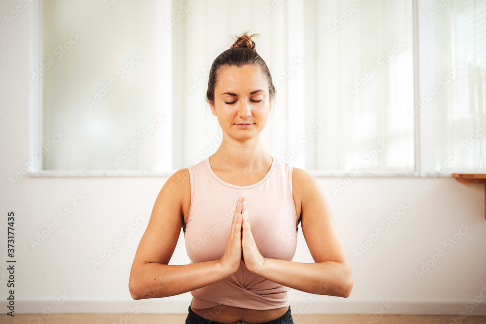 Attractive Caucasian young woman meditating with palms in Namaste at home Attractive Caucasian young woman meditating with palms in Namaste at home