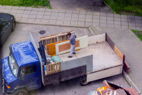 Workers load old furniture into the back of a truck to transport