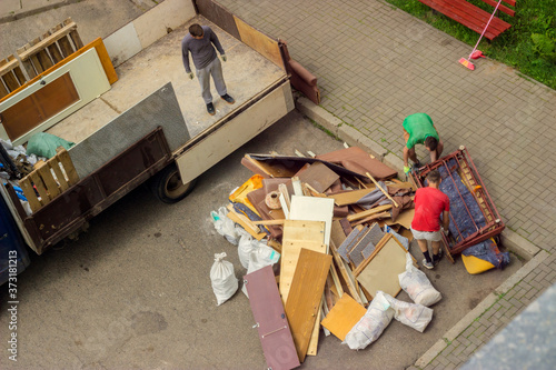 Workers load old furniture into the back of a truck to transport