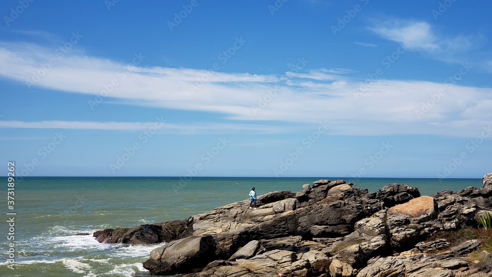 Man on top of the rock, north sea beach at Rio das Ostras, Rio de Janeiro, Brazil. 