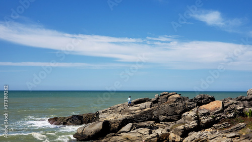 Man on top of the rock, north sea beach at Rio das Ostras, Rio de Janeiro, Brazil. 