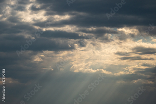 beautiful sun rays shine through the thick heavy cloud in the morning sky after a rain fall © Yi