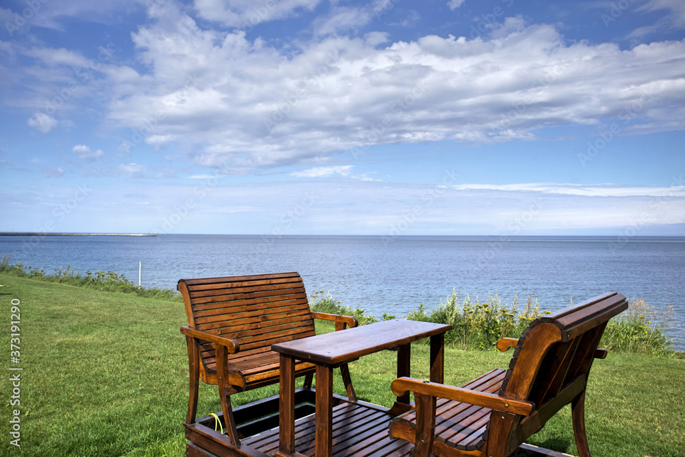 Fototapeta premium Garden swing, table and chairs on the seashore, by the sea.