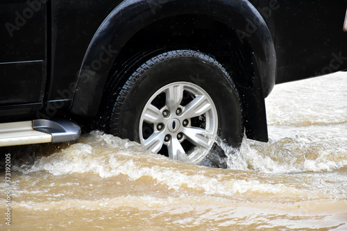 Pickup truck is passing the urban road which fulled of high floodwater in the morning of the heavy raining day.