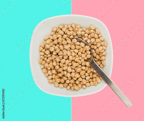 Uncooked raw chickpeas in a plate with spoon in paltel background photo