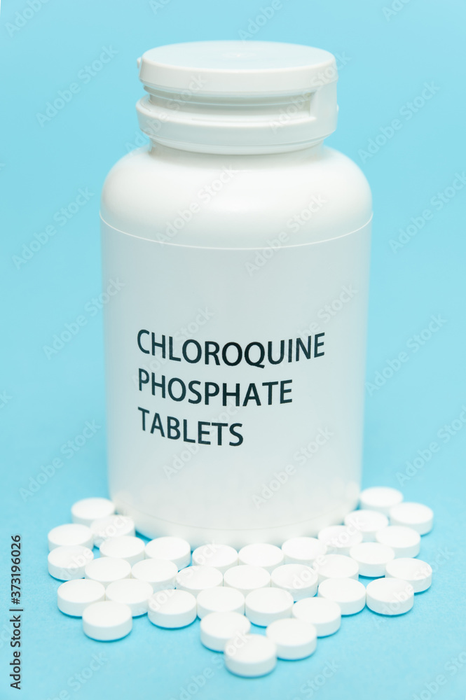 CHLOROQUINE Phosphate in white bottle packaging with scattered pills. Treatments for COVID-19. isolated on blue background. Close-up. Vertical shot. CHLOROQUINE Phosphate in white bottle packaging with scattered pills. Treatments for COVID-19. isolated on blue background. Close-up. Vertical shot.