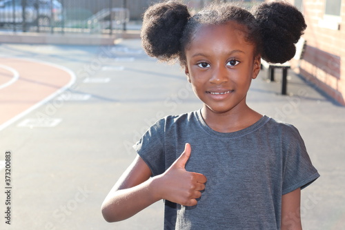 Girl smiling with thumbs up gesture outdoors