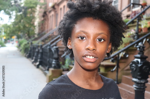Konstfotografi Head shot of black kid standing on city sidewalk near brownstone buildings in ba