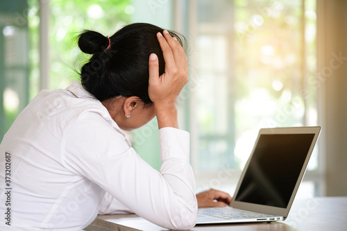 woman sitting down, his face unsettled. At the computer desk she has headaches and stress. Cause of hard work and insufficient rest.