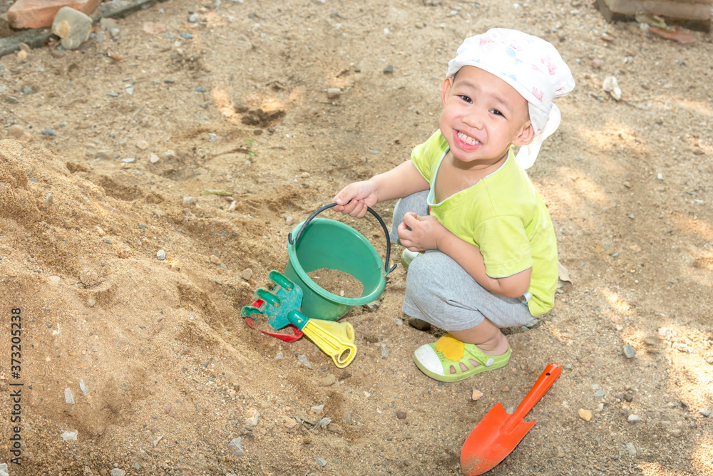 Thai baby boy palying on pile of sand with toy and plastic fork Thai baby boy palying on pile of sand with toy and plastic fork