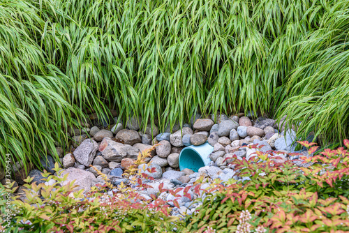 Storm water management in public space, plastic pipe, rocks, and shrub plantings  © knelson20