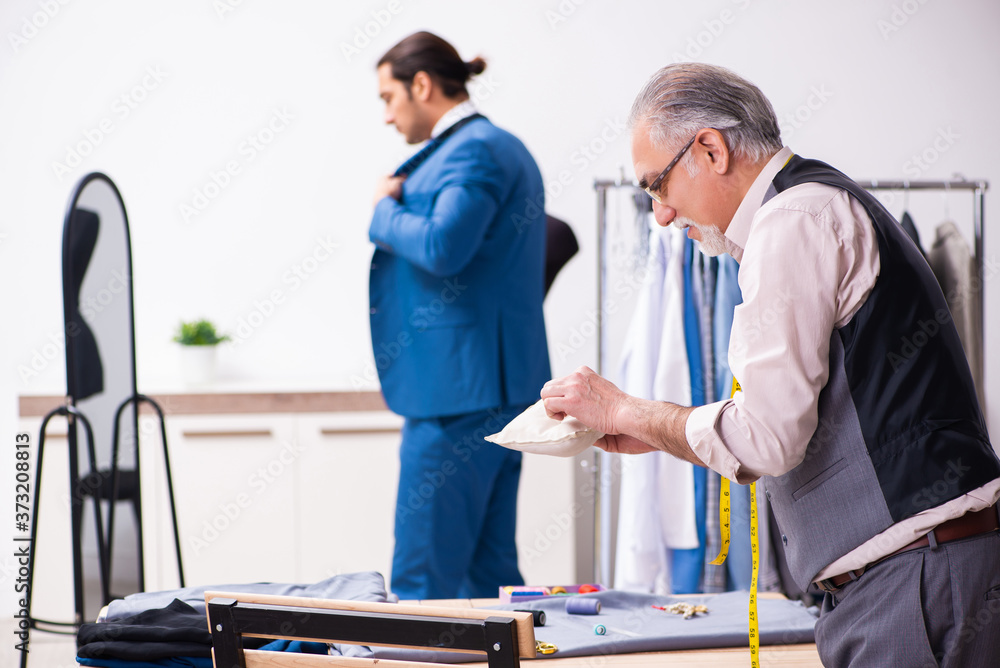 Young businessman visiting old male tailor Young businessman visiting old male tailor