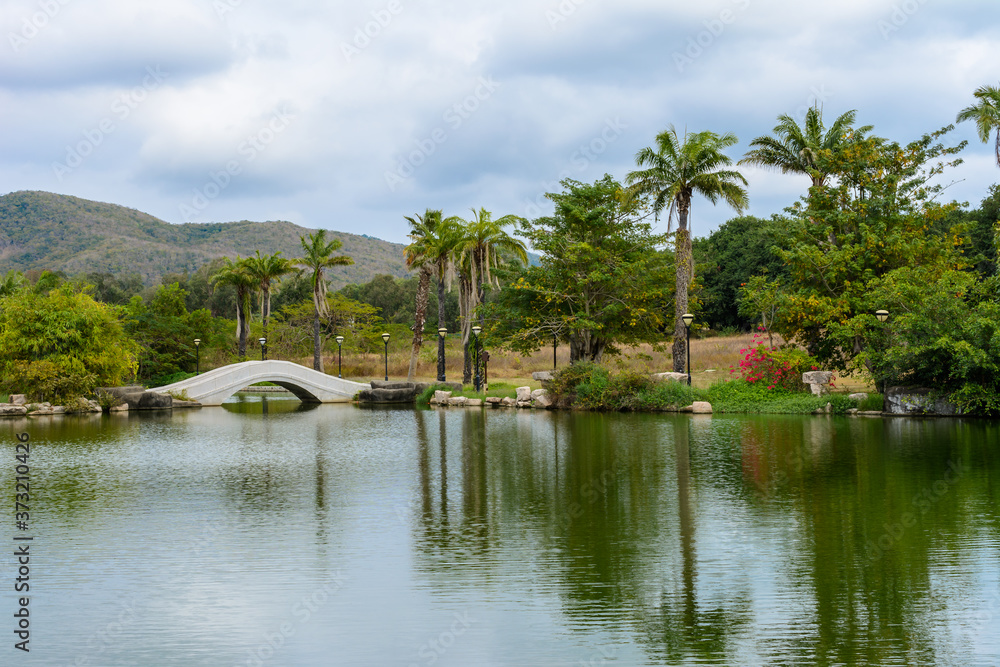 Green lake surrounded by gazebos, temples, mountains, flowers, palm grove and stone fence on the territory of Buddhist center Nanshan. Green lake surrounded by gazebos, temples, mountains, flowers, palm grove and stone fence on the territory of Buddhist center Nanshan.