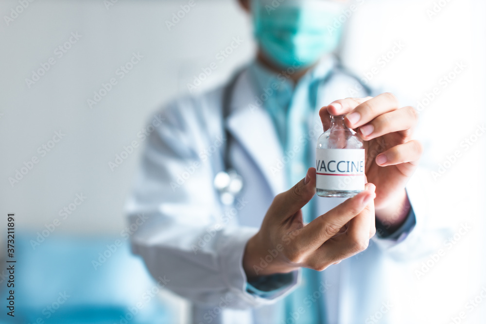 A doctor or scientist in laboratory holding a syringe with liquid vaccines for children or older adults, or cure animal diseases.Close up of a Doctor holding a vaccine. A doctor or scientist in laboratory holding a syringe with liquid vaccines for children or older adults, or cure animal diseases.Close up of a Doctor holding a vaccine.