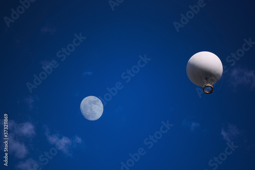 Air excursion balloon with a basket for passengers against the background of a bright blue sky with white clouds. photo