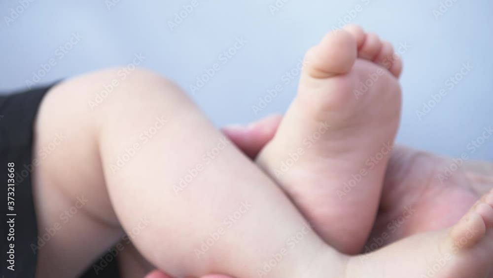 Happy family. Mother's hands hold the baby's legs. The legs of a newborn baby are caressed by a mother. Happy family. Mother's hands hold the baby's legs. The legs of a newborn baby are caressed by a mother.