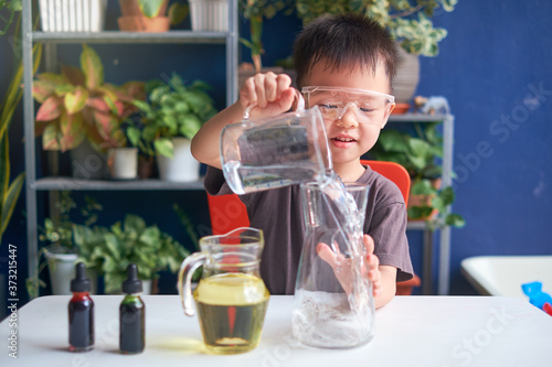 Happy little Asian school kid studying science, making DIY Lava Lamp Science Experiment with oil, water and food coloring, Kid-friendly fun and easy science experiments at home concept