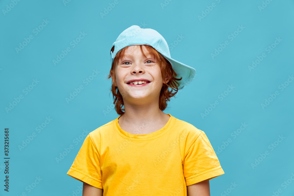 Yellow T-shirt cap on the head boy blue background 