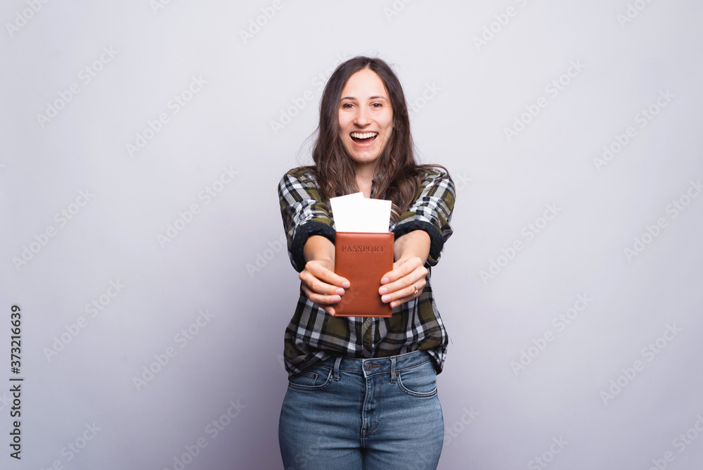 Excited girl is showing to the camera her passport and tickets over white background. Excited girl is showing to the camera her passport and tickets over white background.