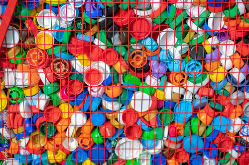 Texture of multi-colored plastic lids in a box of red rods. Recycling of recyclable materials. 