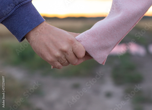 A loving young couple holding hands. Hands of a girl and a guy close-up. On a date boy and girl on the nature