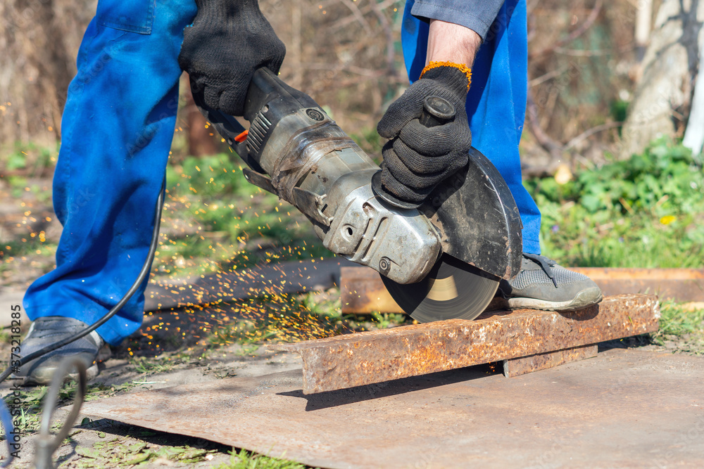 Worker cuts metal with an angle grinder