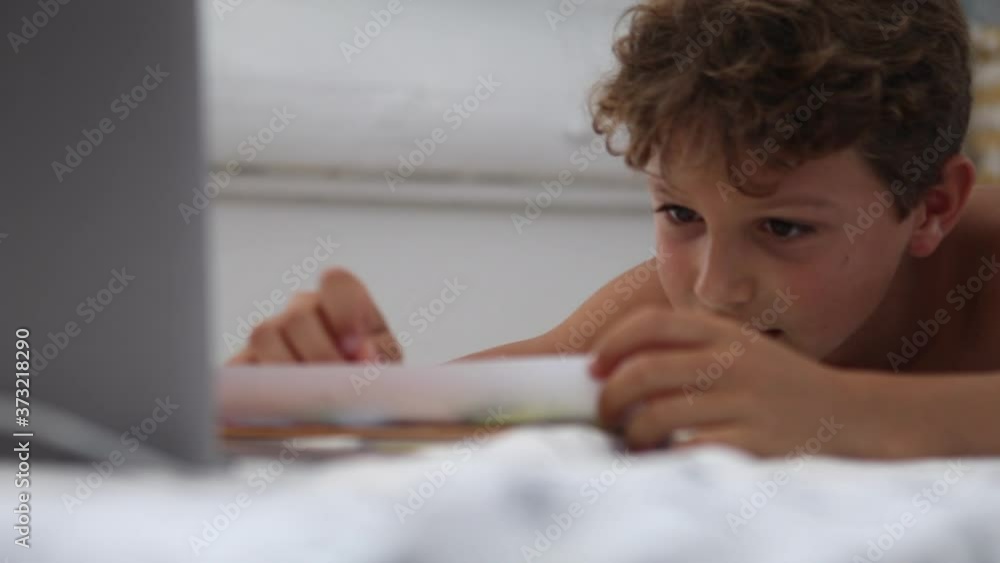 Candid kid doing homework. Authentic child studies online class from home