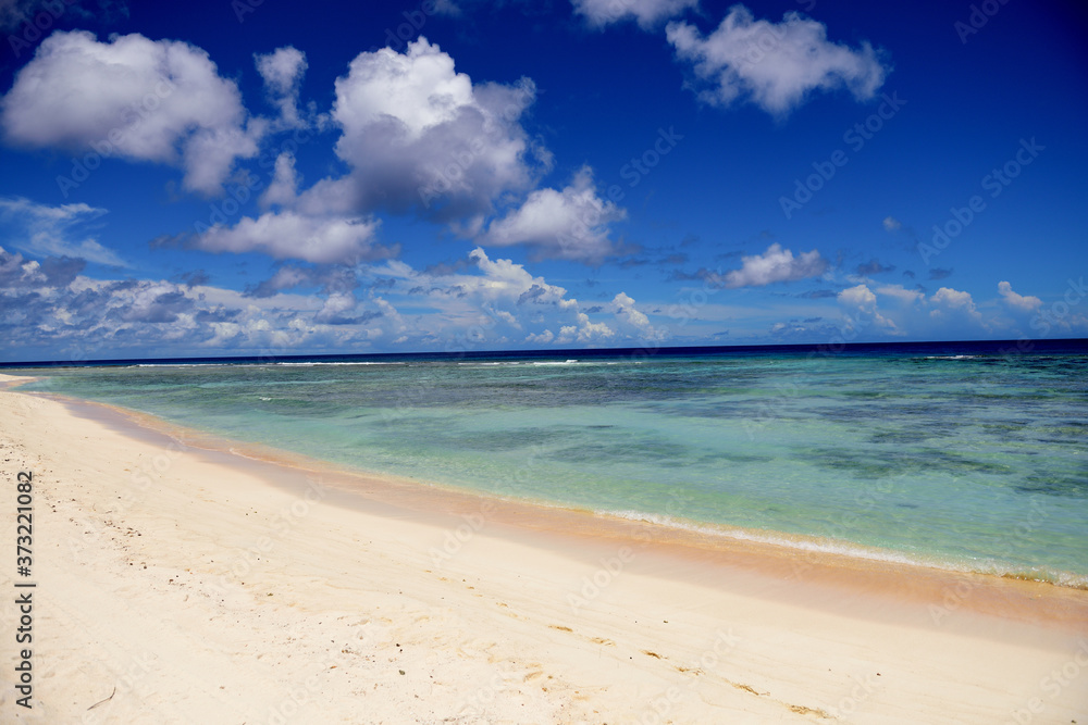 Deserted sunny tropical sandy beach and blue sea with sky and clouds in Guam, Micronesia