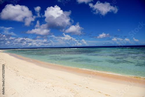 Deserted sunny tropical sandy beach and blue sea with sky and clouds in Guam  Micronesia