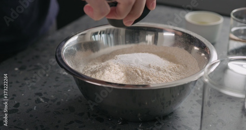add dry ingredients into flour in steel bowl on concrete countertop