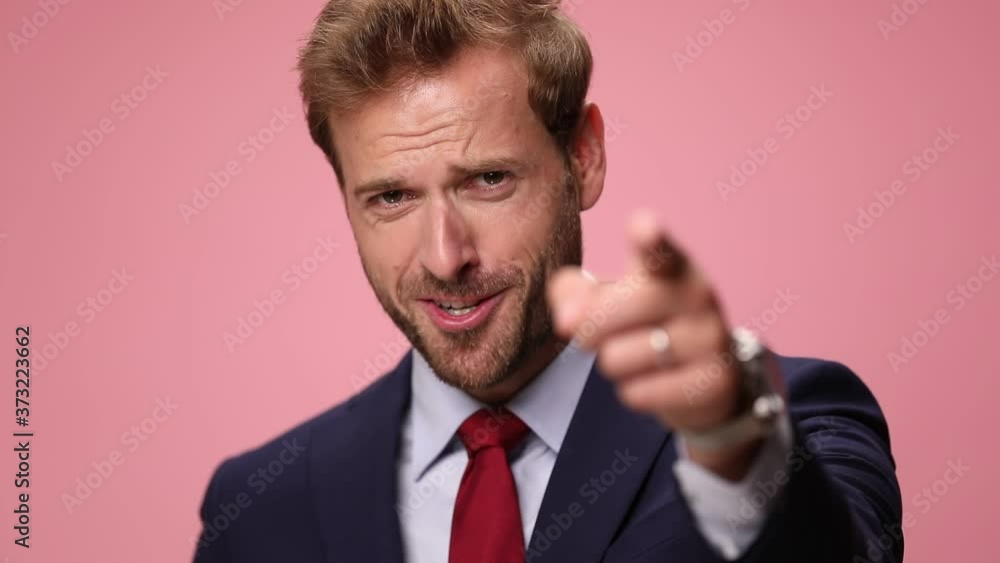 young elegant businessman in navy blue suit looking up, smiling, pointing fingers and laughing, making phone and thumbs up gestures on pink background young elegant businessman in navy blue suit looking up, smiling, pointing fingers and laughing, making phone and thumbs up gestures on pink background