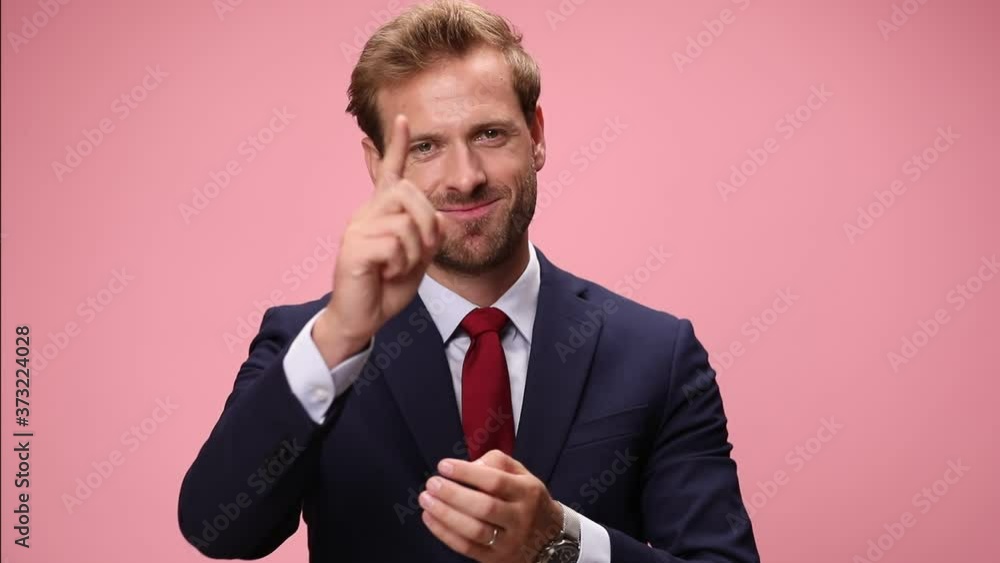 happy attractive young man in navy blue suit smiling, clapping hands, nodding and pointing fingers on pink background happy attractive young man in navy blue suit smiling, clapping hands, nodding and pointing fingers on pink background