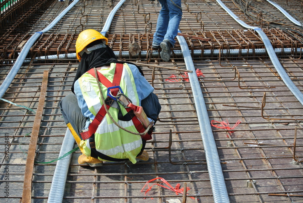 MALACCA, MALAYSIA -MAY 27, 2016: Construction workers fabricating steel reinforcement bar at the construction site in Malacca, Malaysia. The reinforcement bar was tied together using tiny wire.  