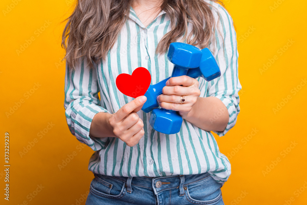 Close up photo of woman hands holding dumbbells and red paper heart. love sport. Close up photo of woman hands holding dumbbells and red paper heart. love sport.