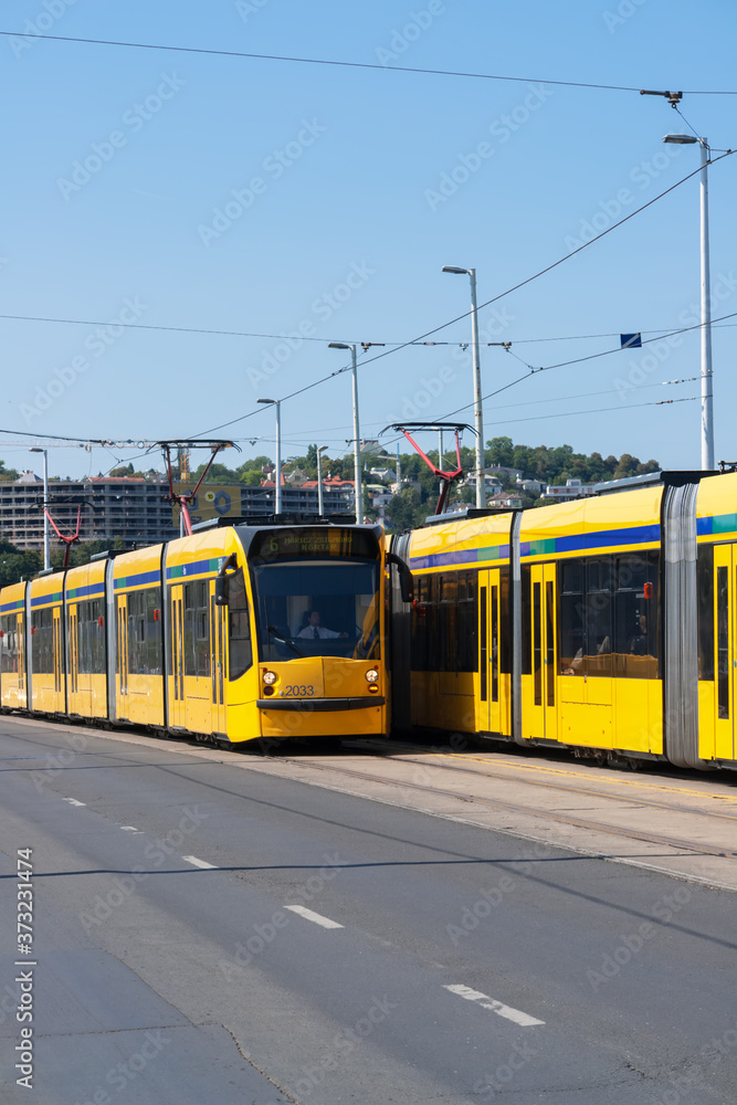 Budapest, Hungary: Two yellow modern tramways in the streets of Budapest