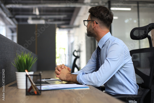 Focused businessman thinking at modern office into report file calculating stock market earnings, startup business.