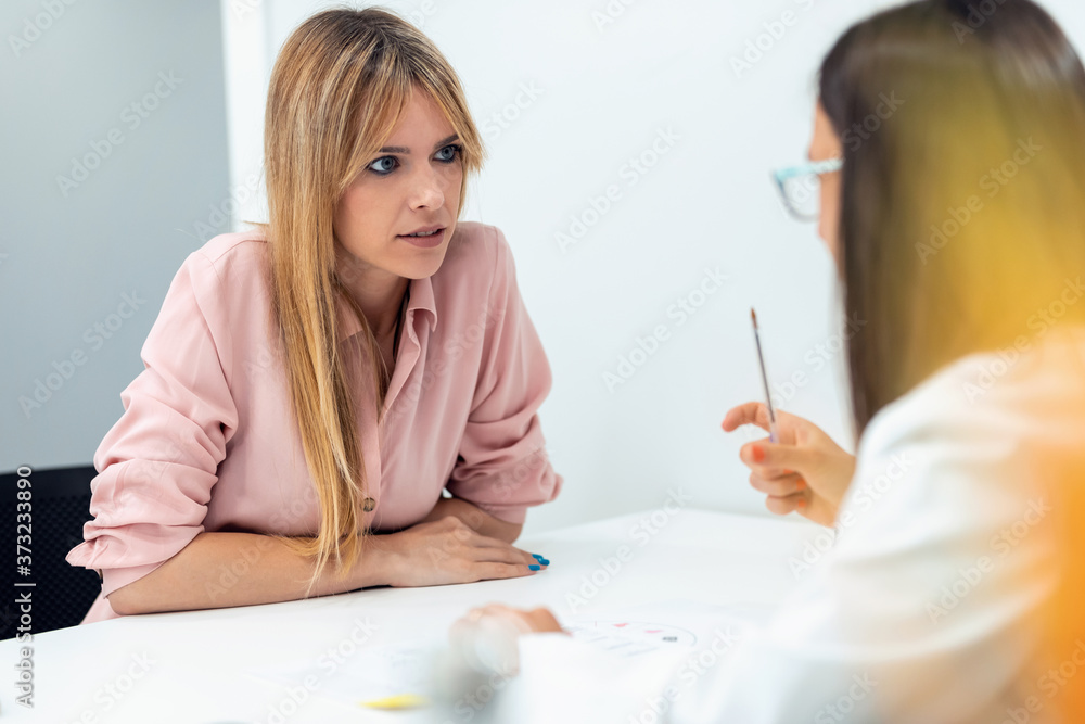 Beautiful young nutritionist woman explaining to her patient thediet he should follow to lose weight in the consultation. Beautiful young nutritionist woman explaining to her patient thediet he should follow to lose weight in the consultation.