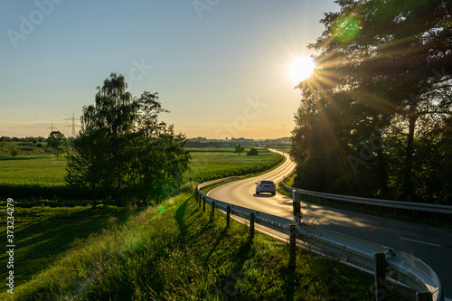 Car driving curvy road on the countryside during sunset