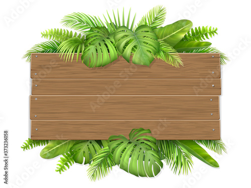 Empty wooden sign decorated with tropical leaves. Billboard with a place for advertising or invitations.