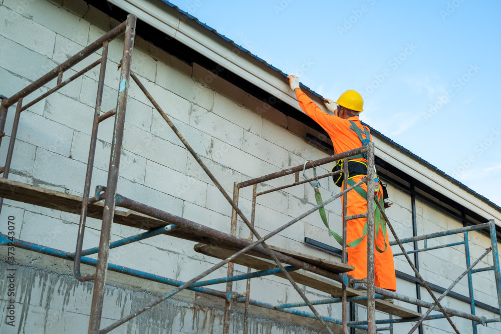 Fototapeta premium Roofer worker in protective uniform wear and safety line working install new roof at construction site.