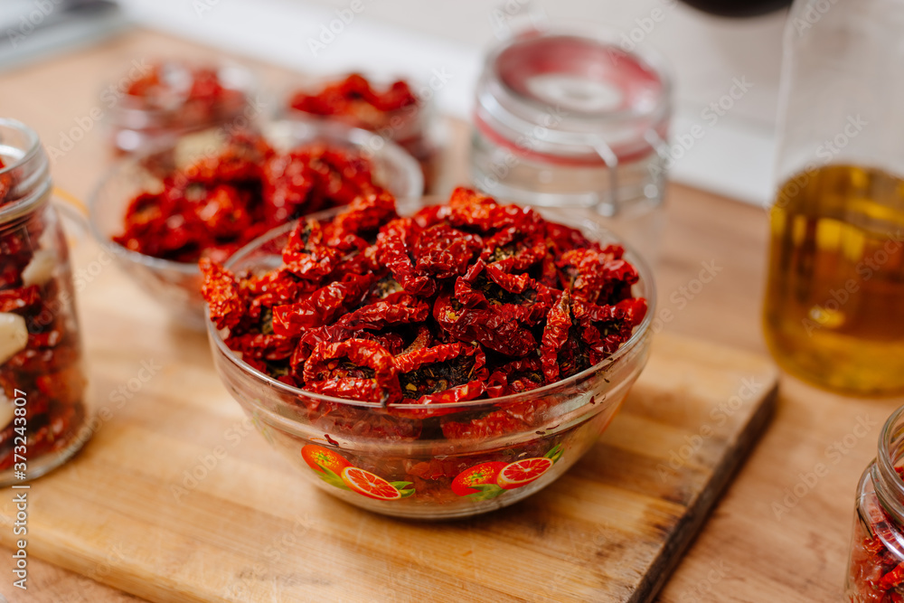 Sun-dried tomatoes. The process of cooking sun-dried tomatoes. The woman is preparing tomatoes in the kitchen. A woman cuts tomatoes, greases them with oil and spices them. Sun-dried tomatoes. The process of cooking sun-dried tomatoes. The woman is preparing tomatoes in the kitchen. A woman cuts tomatoes, greases them with oil and spices them.