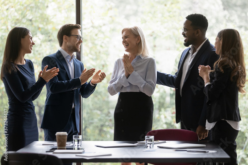 Fotografía Diverse millennial corporate staff greeting aged woman colleague for her contrib