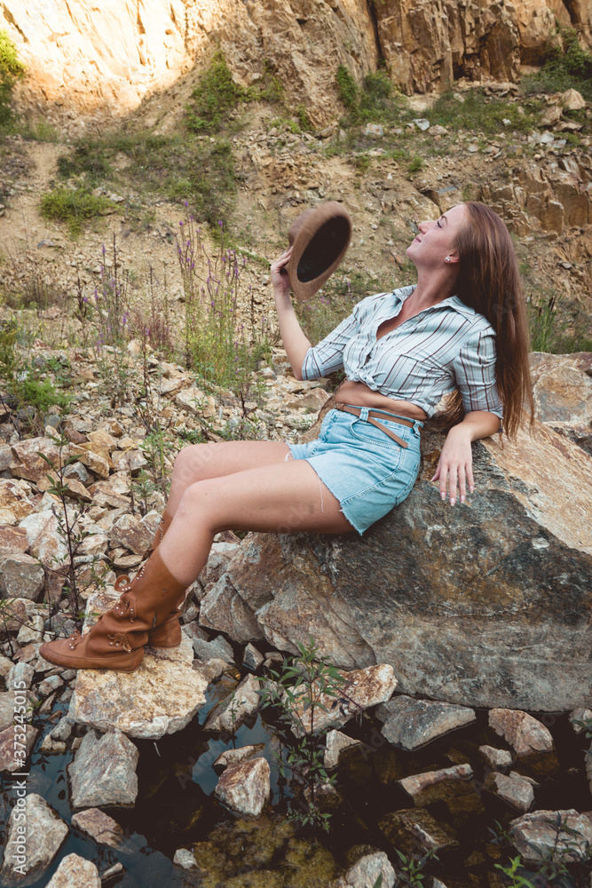 Fototapeta premium Young woman relaxing outdoor travel freedom lifestyle with mountains on background. Fashionable girl in a mountain