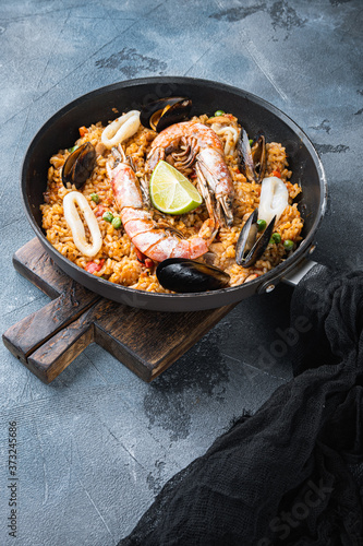 Homemade freshly prepared paella with chicken and seafood on grey textured background