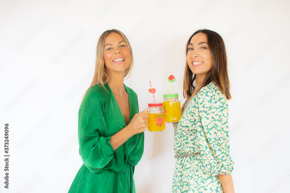 Two friends in green dresses with a cocktail smiling Two friends in green dresses with a cocktail smiling