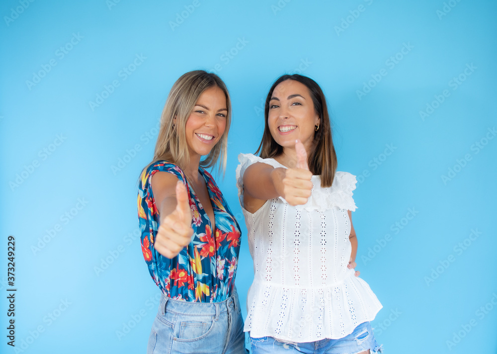 Two friends with summer clothes making finger up gesture
