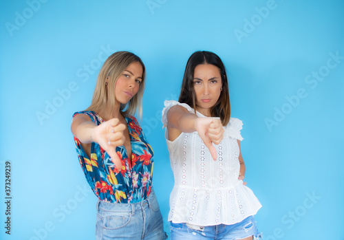 Two friends with summer clothes pose together gesturing