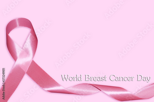 Closeup of pink badge ribbon on woman chest to support breast cancer cause. Healthcare, medicine and breast cancer awareness concept.
