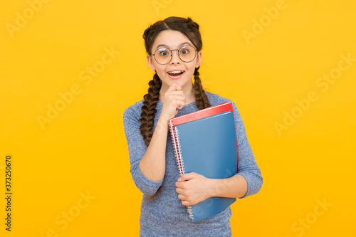 What a surprise. Surprised child hold books yellow background. Little girl open mouth with surprise. Small kid feel surprise. Surprising information. School library. Education and study. Big surprise